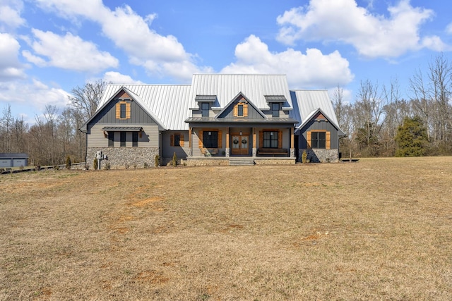 modern farmhouse style home with covered porch, a front yard, a standing seam roof, metal roof, and stone siding