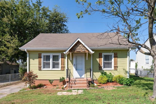 bungalow-style home with central air condition unit and a front lawn