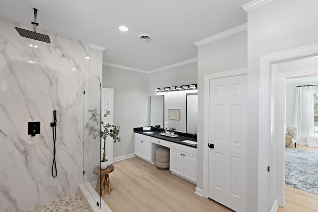 full bathroom featuring wood finished floors, visible vents, ornamental molding, a marble finish shower, and double vanity