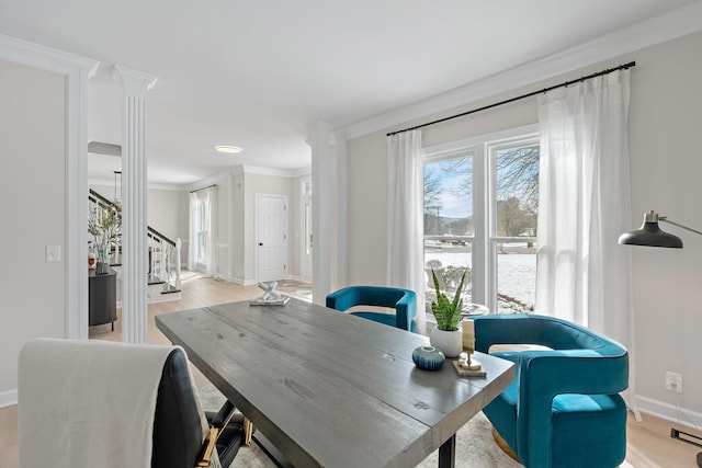 office space featuring baseboards, ornate columns, light wood-style floors, and crown molding