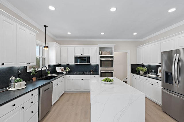 kitchen with a sink, white cabinets, appliances with stainless steel finishes, dark stone counters, and decorative light fixtures