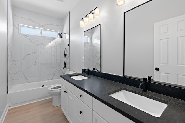 bathroom with toilet, wood finished floors, a sink, and bathing tub / shower combination