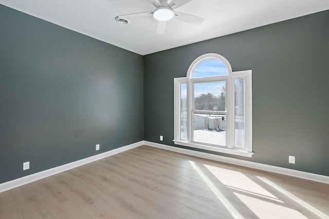 spare room featuring light wood-type flooring, baseboards, visible vents, and ceiling fan