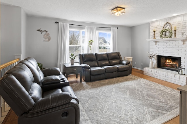 living room with wood-type flooring, a brick fireplace, and a textured ceiling