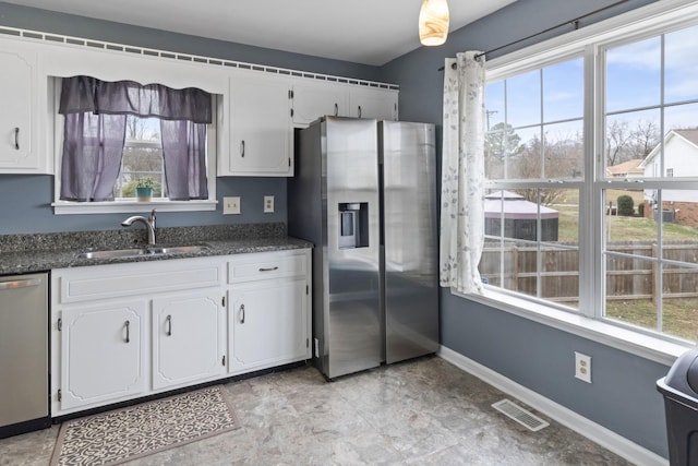 kitchen with stainless steel appliances, white cabinetry, sink, and a wealth of natural light