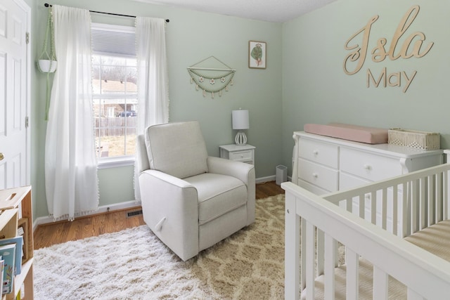 bedroom featuring a nursery area and light wood-type flooring