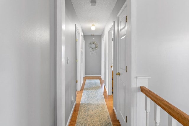 corridor featuring light hardwood / wood-style flooring and a textured ceiling