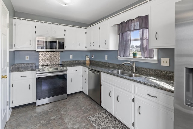 kitchen with white cabinetry, sink, stainless steel appliances, and dark stone counters