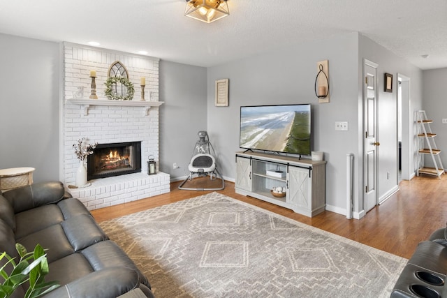 living room with hardwood / wood-style flooring, a textured ceiling, and a fireplace