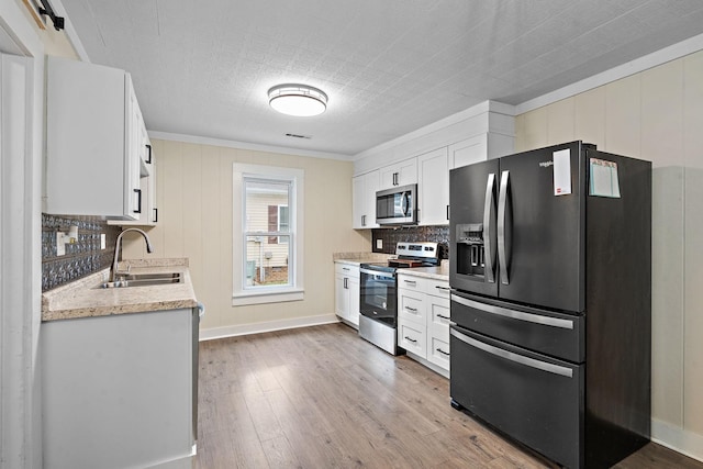 kitchen featuring sink, white cabinetry, stainless steel appliances, light hardwood / wood-style floors, and decorative backsplash