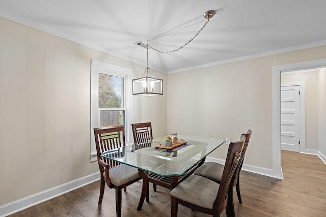 dining area with hardwood / wood-style flooring, ornamental molding, and a notable chandelier