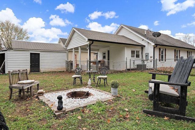 back of house featuring an outdoor structure, a yard, and a fire pit