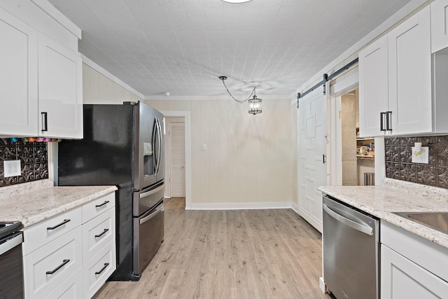 kitchen featuring white cabinetry, pendant lighting, stainless steel appliances, and a barn door