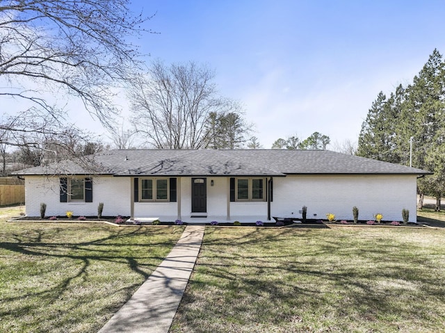 view of front facade featuring brick siding, a chimney, a front lawn, and roof with shingles