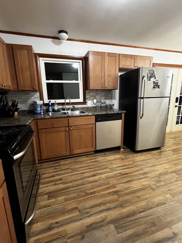 kitchen with stainless steel appliances, hardwood / wood-style flooring, sink, and decorative backsplash