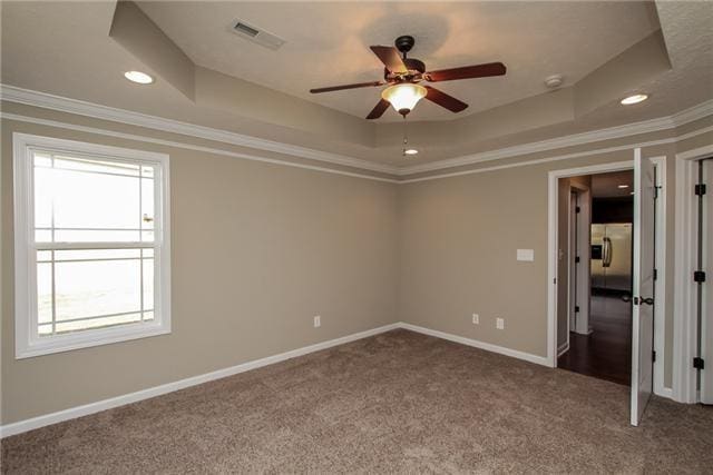 carpeted empty room with crown molding, ceiling fan, and a raised ceiling