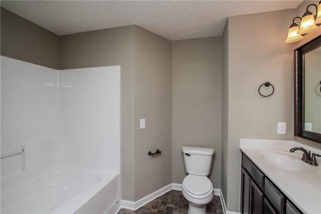 bathroom featuring a washtub, vanity, toilet, and a textured ceiling