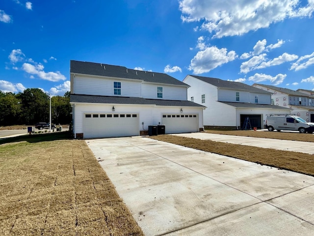 front of property with a garage, central air condition unit, and a front lawn