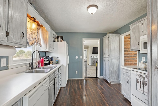 kitchen featuring dark hardwood / wood-style floors, white cabinetry, sink, white appliances, and a textured ceiling