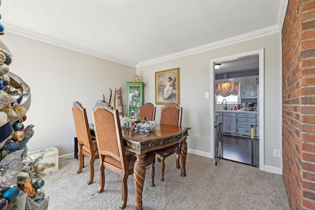 dining room featuring sink, ornamental molding, a textured ceiling, and carpet flooring