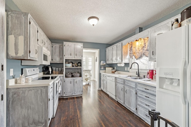 kitchen with sink, white appliances, dark wood-type flooring, and a textured ceiling