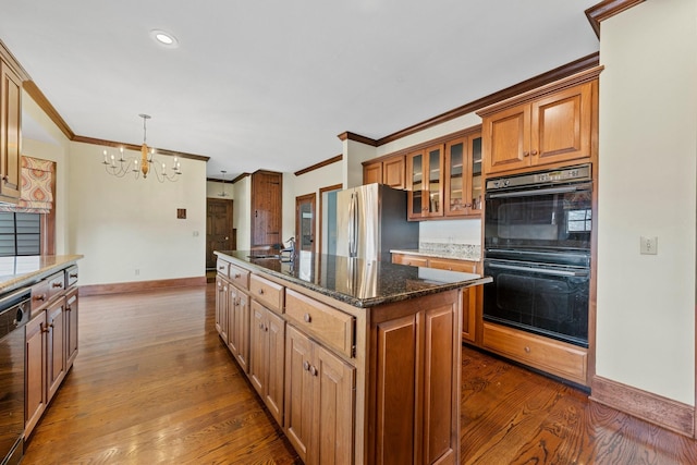 kitchen featuring dark wood-type flooring, a center island with sink, appliances with stainless steel finishes, pendant lighting, and dark stone counters