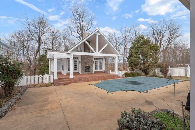 back of house featuring a patio, a covered pool, and french doors