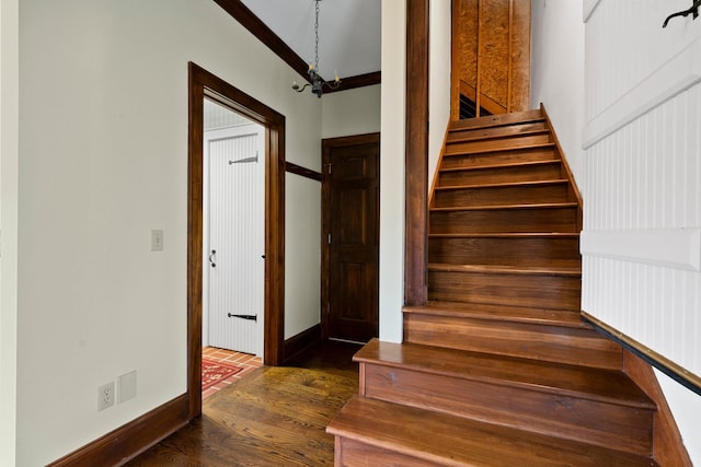 stairway featuring an inviting chandelier, crown molding, and hardwood / wood-style floors