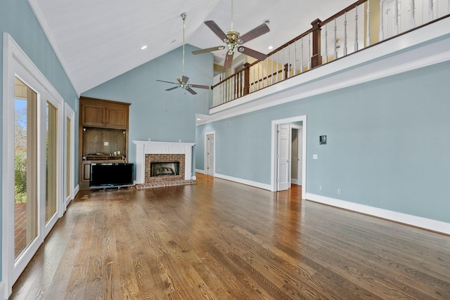 unfurnished living room with dark wood-type flooring, ceiling fan, a fireplace, and high vaulted ceiling