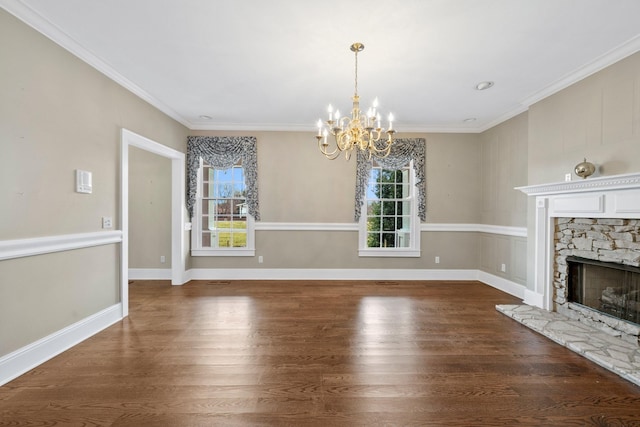 unfurnished living room featuring dark wood-type flooring, a stone fireplace, a chandelier, and crown molding