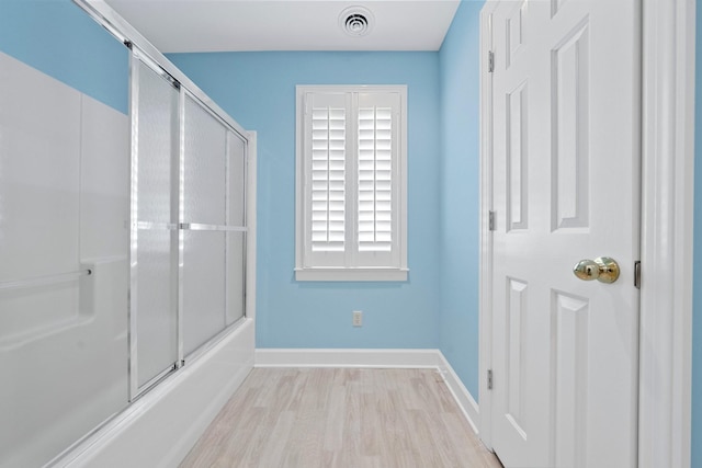 bathroom featuring hardwood / wood-style flooring and shower / bath combination with glass door