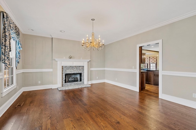 unfurnished living room with crown molding, dark wood-type flooring, an inviting chandelier, and a fireplace