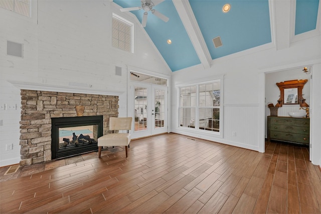 living area with hardwood / wood-style floors, a stone fireplace, french doors, and ceiling fan