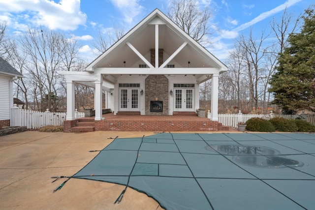 back of property featuring a covered pool, a patio area, and french doors