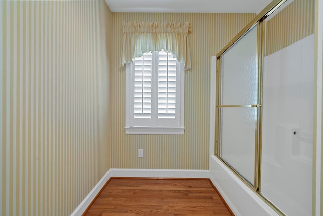 bathroom featuring bath / shower combo with glass door and hardwood / wood-style floors