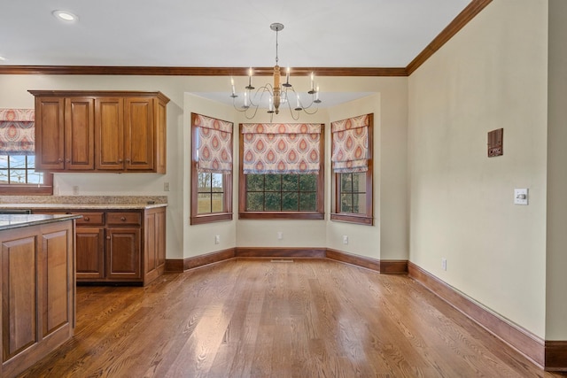 kitchen featuring light stone counters, a chandelier, hanging light fixtures, ornamental molding, and dark hardwood / wood-style flooring