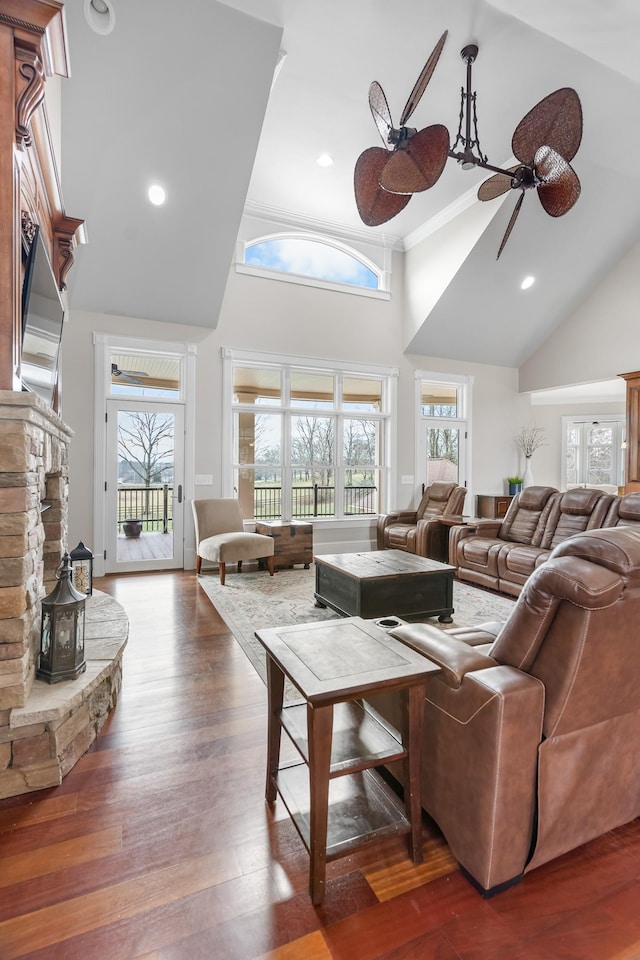 living room with dark hardwood / wood-style floors, a fireplace, ceiling fan, and a towering ceiling