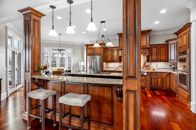 kitchen featuring ornamental molding, appliances with stainless steel finishes, decorative light fixtures, and light stone countertops