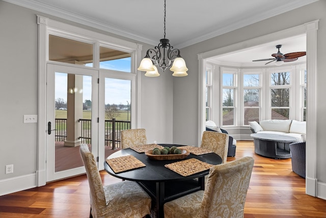 dining room with ceiling fan with notable chandelier, ornamental molding, and hardwood / wood-style floors