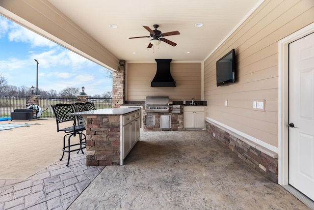 view of patio / terrace featuring ceiling fan, an outdoor kitchen, area for grilling, and a wet bar