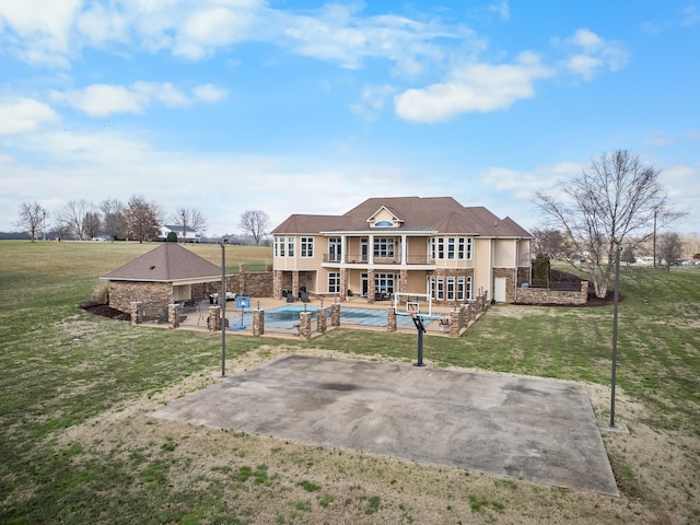 back of property featuring a swimming pool with hot tub, a balcony, a yard, and a patio area