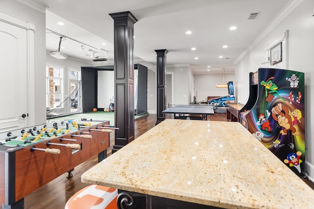 kitchen with ornate columns, light stone counters, decorative light fixtures, a center island, and ornamental molding