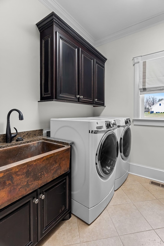 clothes washing area featuring sink, crown molding, cabinets, light tile patterned floors, and washer and clothes dryer