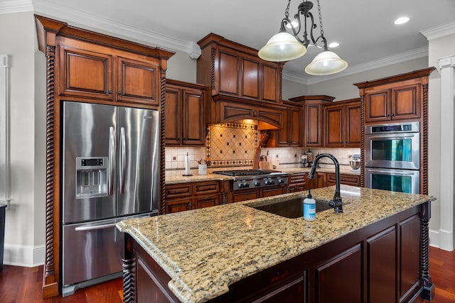 kitchen featuring light stone counters, sink, stainless steel appliances, and a center island with sink