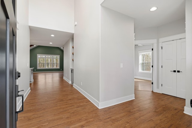 hallway with a wealth of natural light, light wood-style flooring, baseboards, and recessed lighting