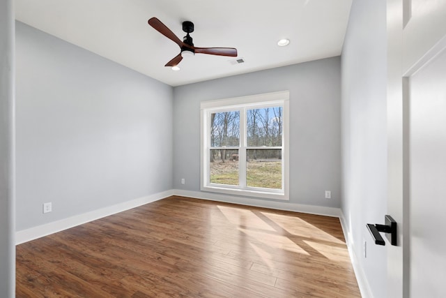 empty room with ceiling fan, wood finished floors, visible vents, and baseboards