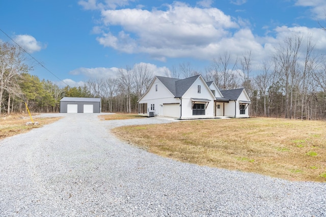 view of front of property with a detached garage, a front lawn, and roof with shingles