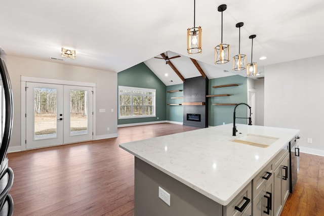 kitchen featuring a fireplace, a ceiling fan, dark wood-type flooring, vaulted ceiling, and a sink