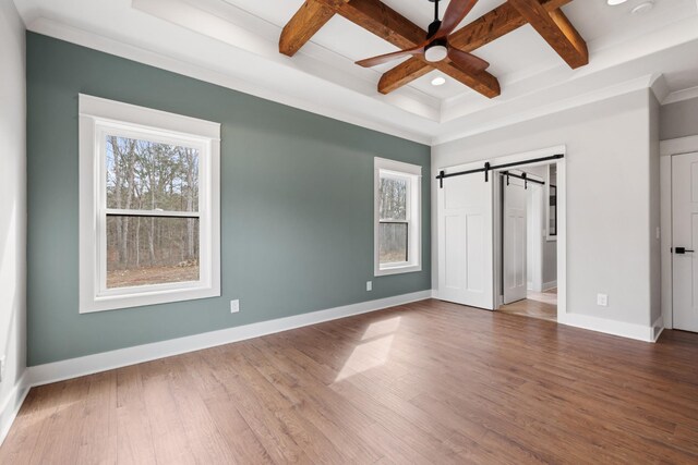 unfurnished bedroom featuring beam ceiling, a barn door, wood finished floors, coffered ceiling, and baseboards