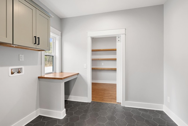 clothes washing area with washer hookup, cabinet space, dark tile patterned floors, and baseboards